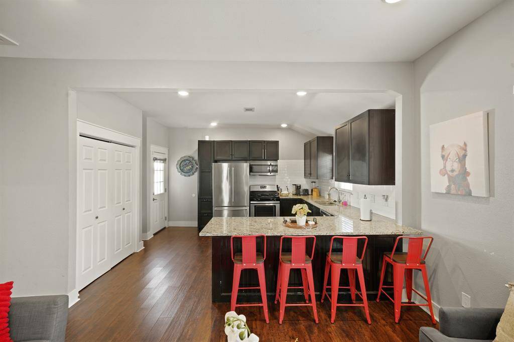 This bedroom features a modern and clean design with neutral walls and hardwood floors. It includes a ceiling fan, ample natural light, and double doors leading to a closet. The room connects to a cozy living area, adding to its convenience and appeal.