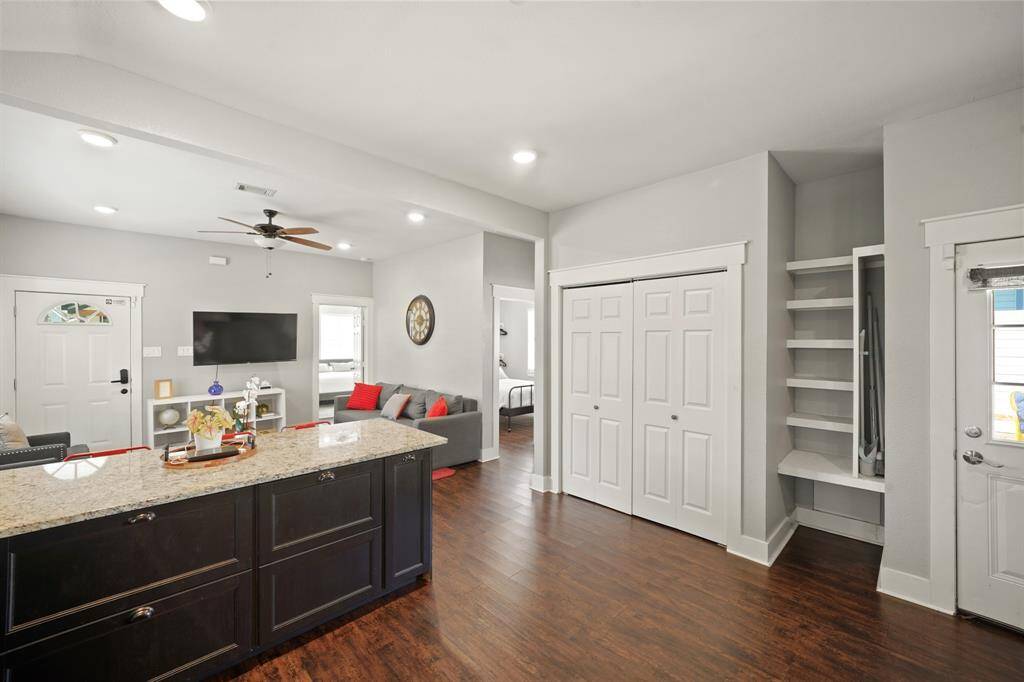 This kitchen features sleek dark cabinets, stainless steel appliances, and a spacious granite countertop. It has wood flooring and ample natural light through a window by the sink, creating a modern and inviting space.