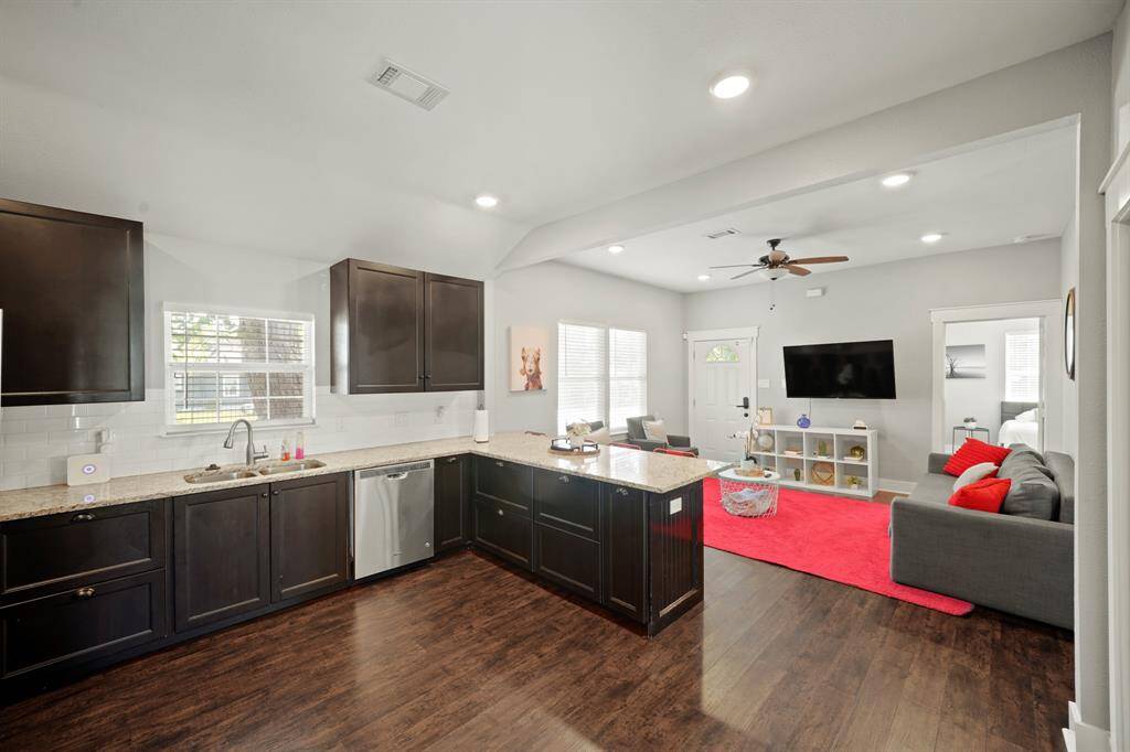 Charming two-story triplex back upstairs unit with white trim, featuring an exterior staircase leading to a small balcony. The property has a paved driveway and is situated on a corner, offering ample natural light.