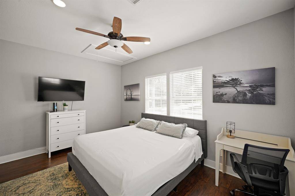 cozy open-concept living area with a modern kitchen. It features wood flooring, light gray walls, and a comfortable seating area with a gray sofa and accent chair. The kitchen has stainless steel appliances and a wooden countertop, creating a welcoming and functional space.