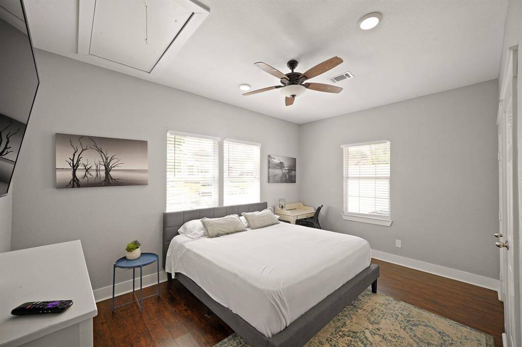 Modern kitchen with stainless steel appliances, gray cabinets, and wood flooring. Bright and inviting with ample natural light from two large windows.