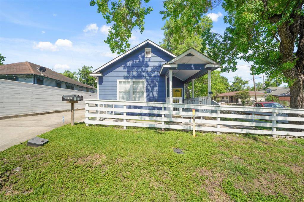 Charming covered balcony with a cozy seating area, perfect for relaxing and enjoying the view of neighboring homes. Bright and welcoming with a "Welcome" mat at the entrance.