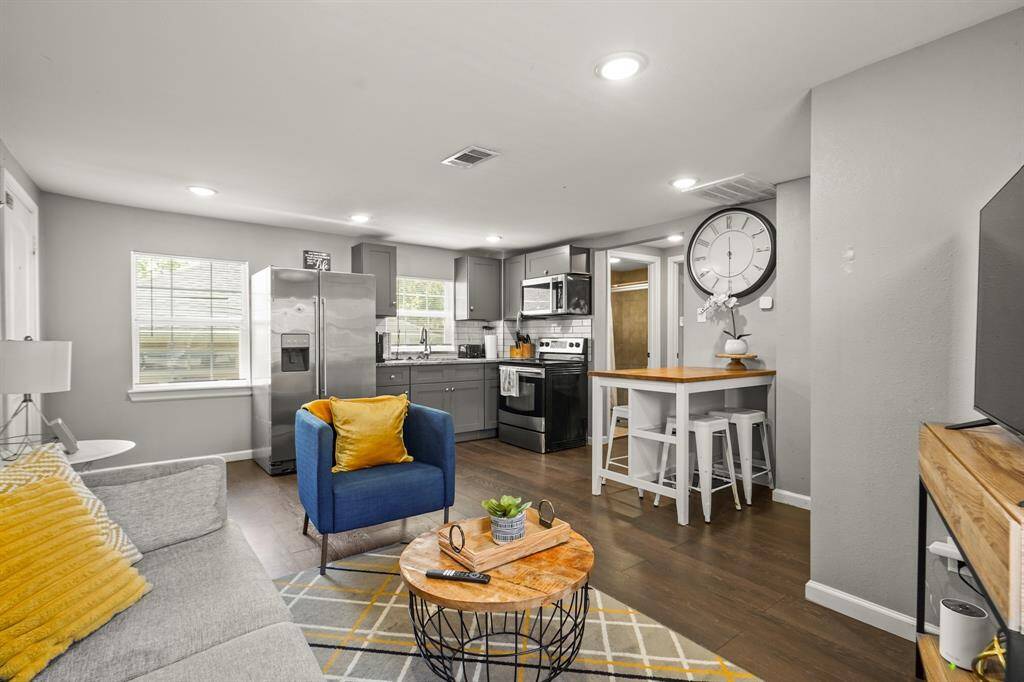 This kitchen features modern gray cabinetry, stainless steel appliances, and a sleek countertop. Ample natural light comes through a window above the sink, complemented by white subway tile backsplash for a clean, contemporary look.