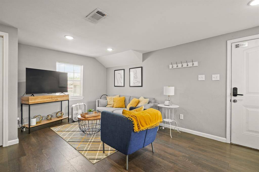 This vibrant room features a cozy built-in seating area with red cushions and colorful pillows. The walls are adorned with bold artwork, including a surfboard and a large mural. The space has a contemporary feel, enhanced by the tiled flooring and modern light fixture. Perfect for a stylish hangout or reading nook.