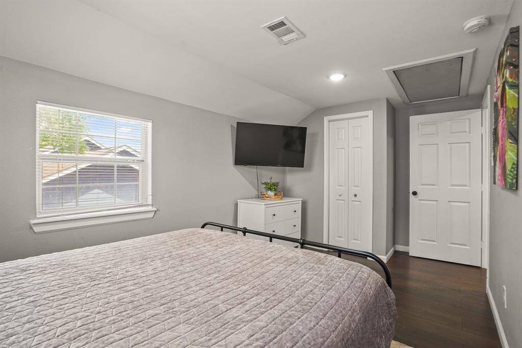 This bathroom features a modern design with neutral tones, a sleek vanity, a large mirror, and a striped shower curtain. Natural light enters through a window, enhancing the bright, airy feel.
