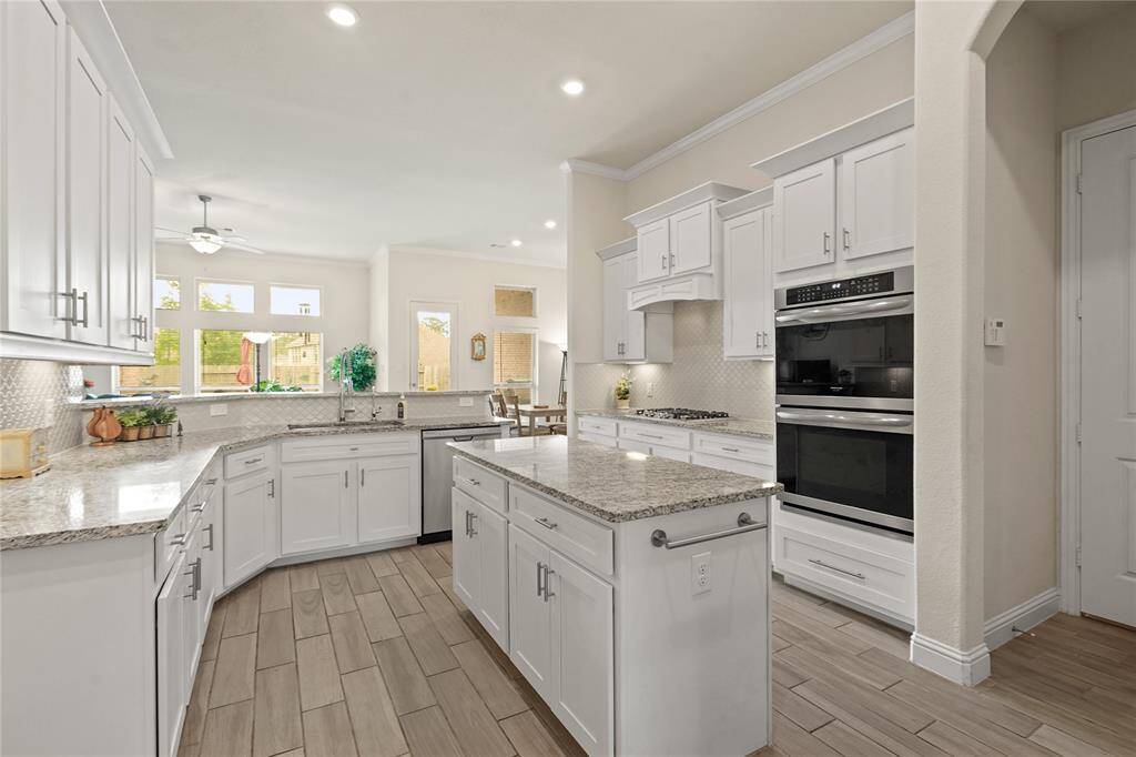 Flooded with natural light, the kitchen features crisp white cabinetry, sleek stainless appliances, and stunning granite countertops.