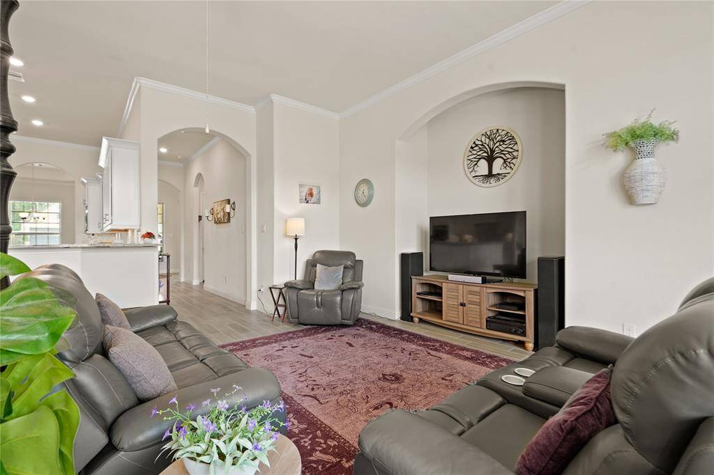 This inviting living room features neutral walls, comfortable seating, and a cozy atmosphere. It includes a large TV, elegant decor, and an open view into the kitchen, creating a seamless flow for entertaining.