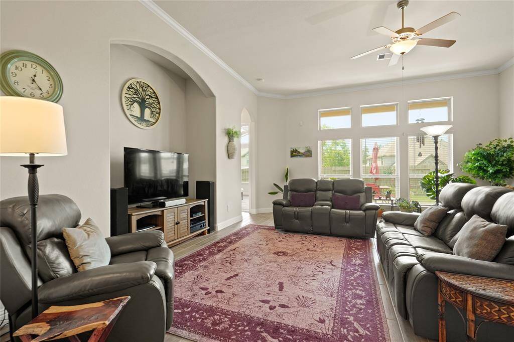 Bright and inviting living room with large windows, ceiling fan, and ample seating featuring an inset for the TV.