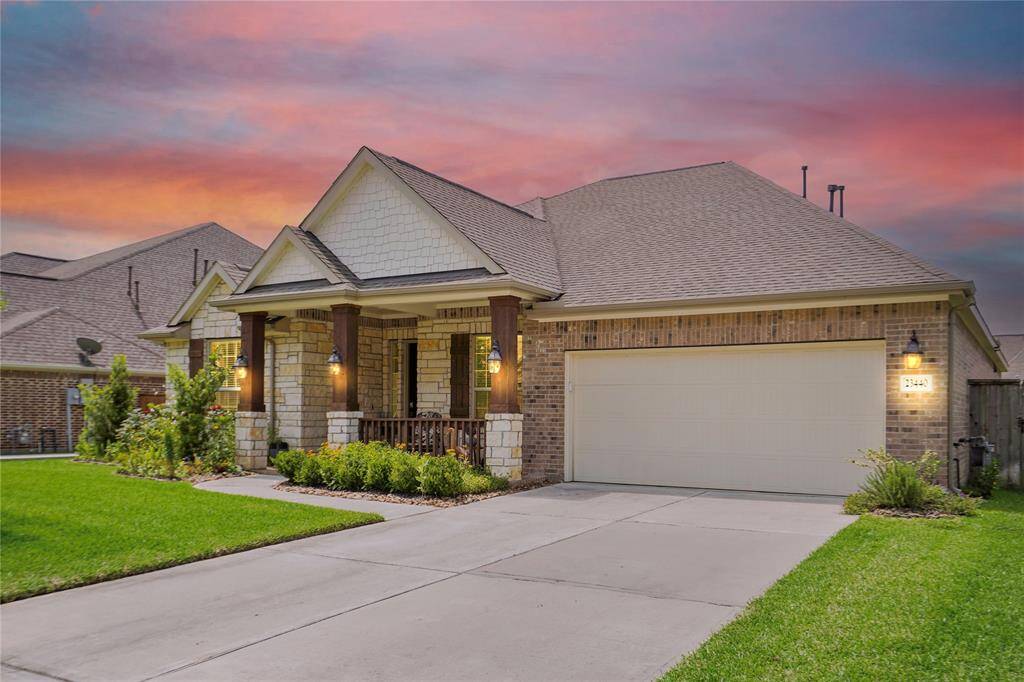 This charming home features a brick exterior with a welcoming front porch, complemented by elegant columns and well-maintained landscaping. The property includes a spacious driveway leading to a three-car tandem garage, all set against a beautiful sunset backdrop.