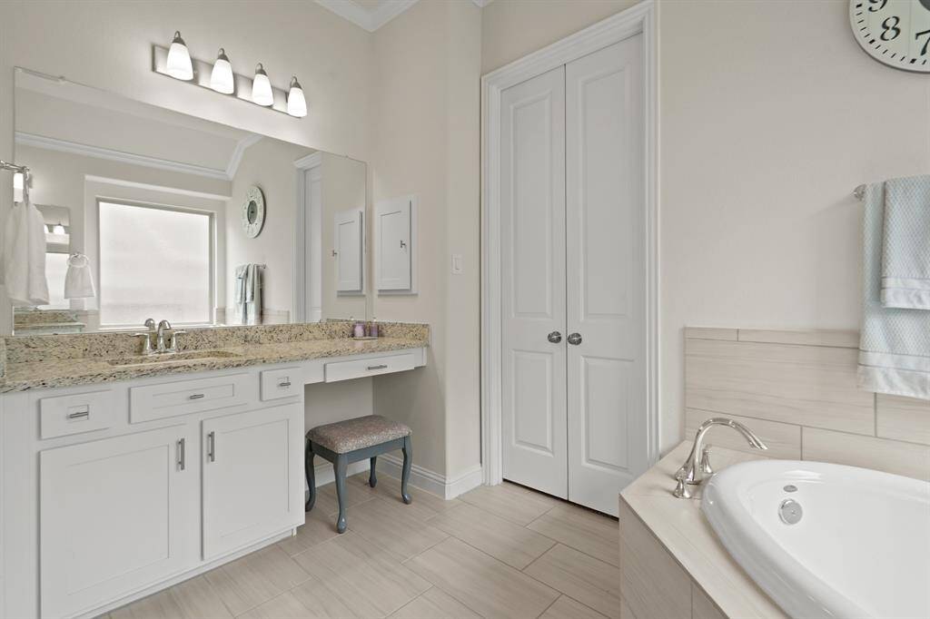 Elegant double doors beside the vanity lead to a spacious walk-in closet.