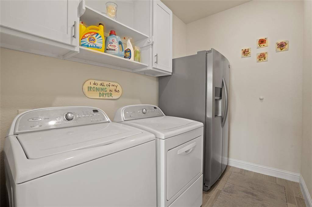 Conveniently located near the kitchen, this laundry room offers space for a second refrigerator and has built-ins cabinets and shelves.