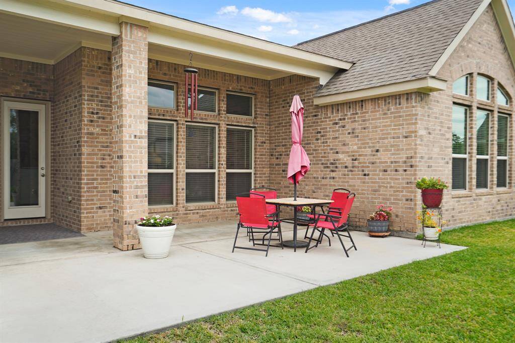 Enjoy outdoor grilling on this inviting covered patio, overlooking a lush backyard.