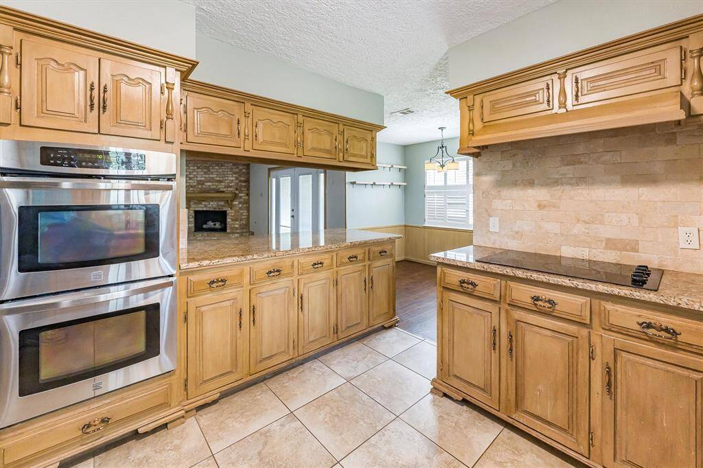 The kitchen opens to the living space and breakfast room, and has a breakfast bar, double oven and glass cooktop