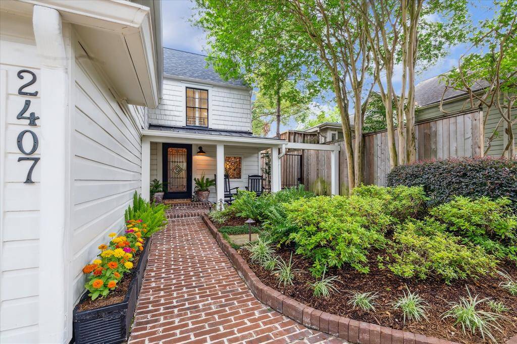 Lovely brick sidewalk leads you to the covered porch where rocking chairs await. Notice the mature low maintenance landscaping.