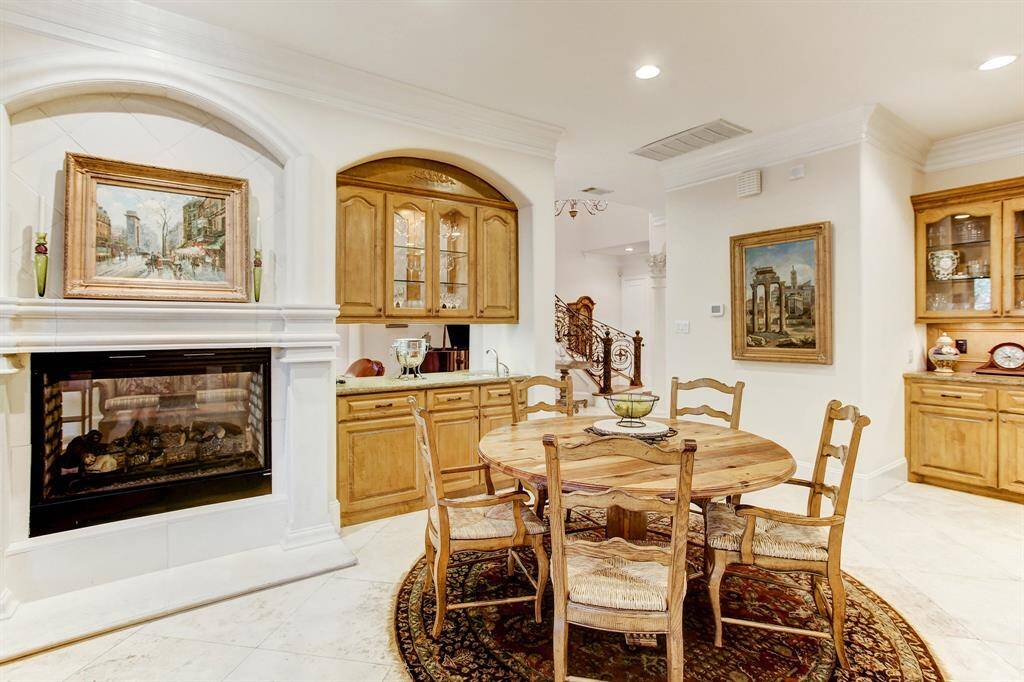 Another photo with a close up of the dual fireplace, breakfast area and wet bar.