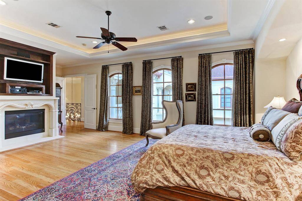 Another view of the primary bedroom focusing on the fireplace and the beautiful arched windows letting in the morning light.