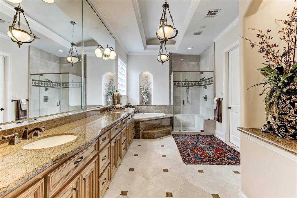 The spacious primary bath has marble floors with granite inserts, granite counters with dual sinks, soaking tub and large shower.  There is a large walk-in closet to the right and is 1 of 2 closets in the primary bath.