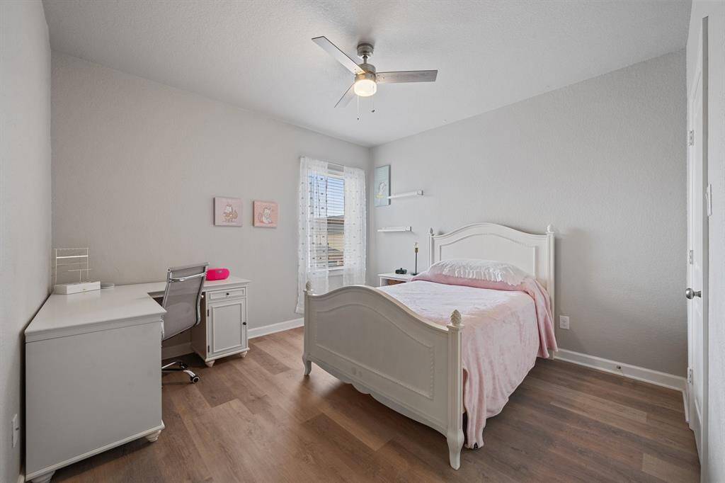 Enjoy the perfect retreat in this bedroom with its elegant luxury vinyl plank flooring, ceiling fan, and window adorned with privacy blinds for added comfort and tranquility.
