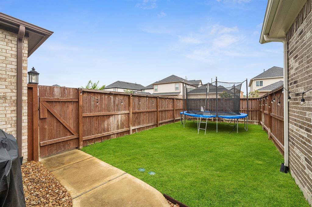 The backyard features a lush green lawn, fully fenced for privacy and security, offering a perfect space for outdoor activities and relaxation.