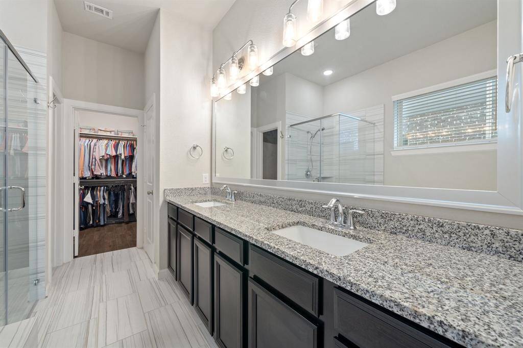 The primary bathroom features a spacious double-sink vanity, elegant tile flooring, and a generous walk-in closet, combining style and functionality for your daily routine.