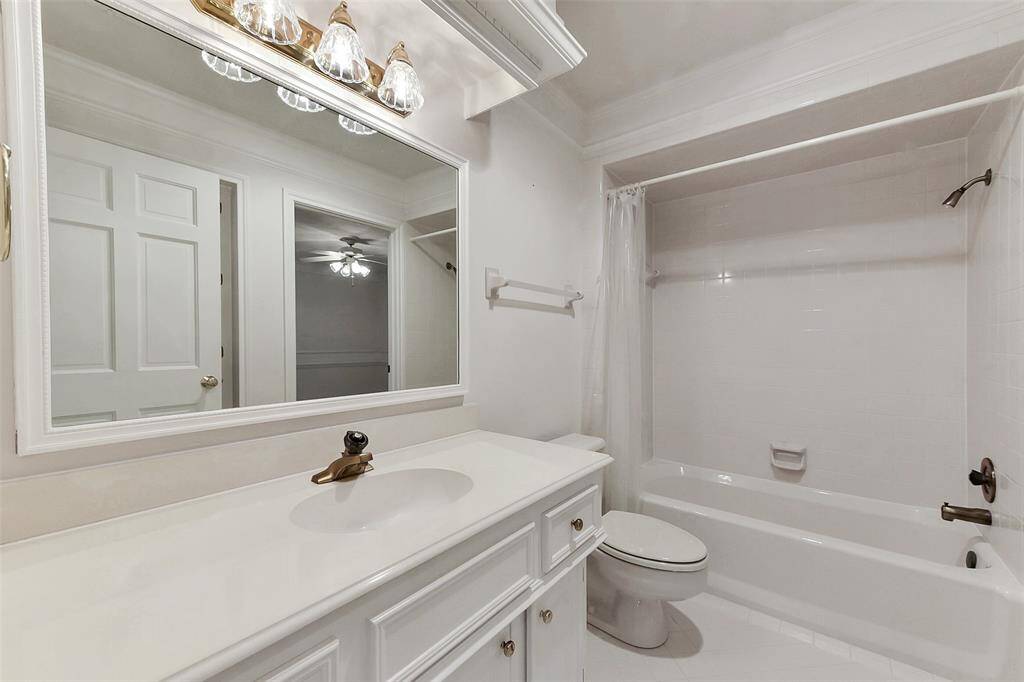 This photo shows a clean, bright bathroom with a large mirror, white cabinetry, and a bathtub with a shower. The lighting is elegant, and the space has been well-maintained.