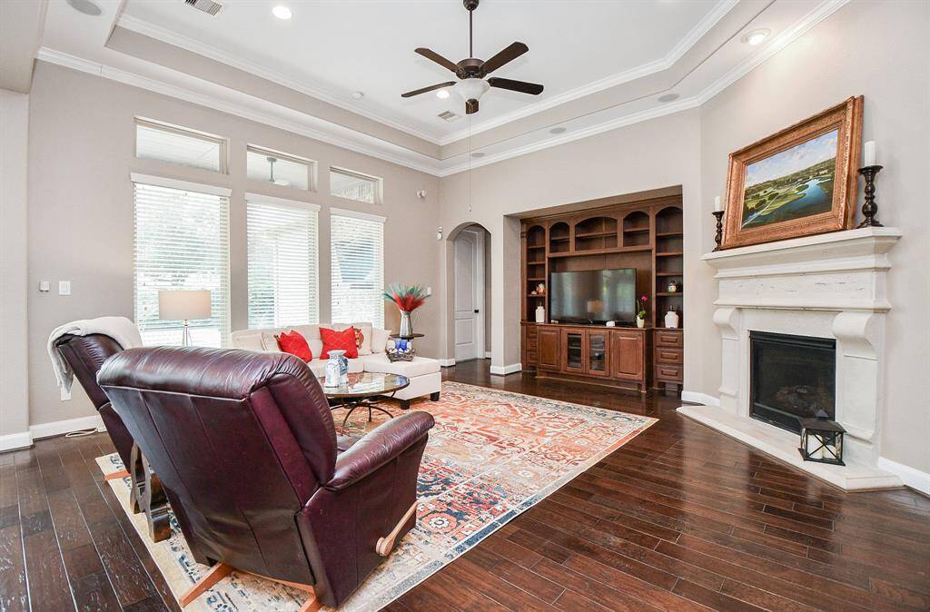 Living room features beautiful flooring, aceiling fan, high ceilings, and a wallof windows.