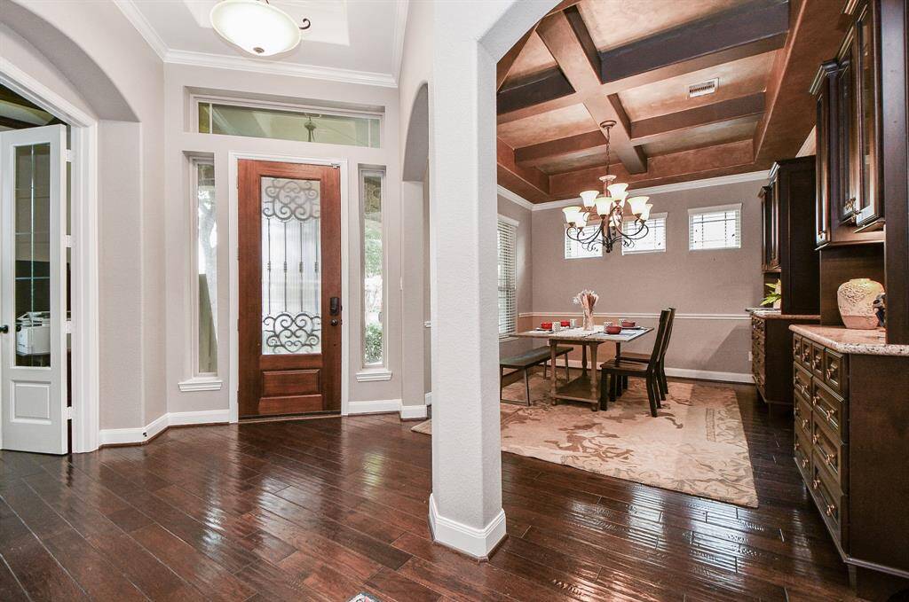 Upon entering are beautiful floors and the dining room with beamed ceilings, custom paint, crown molding, chandelier, and large windows.
