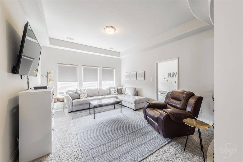 The spacious upstairs game room offers the perfect setting for a game of pool, movie nights, casual lounging, or weekend fun. A trio of windows fills the room with natural light while the tray ceiling adds a touch of architectural interest.
