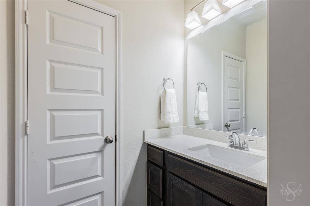 The Hollywood bath offers a sleek vanity with rich cabinetry, granite counters, and modern lighting. Convenient design allows for shared use while maintaining privacy.
