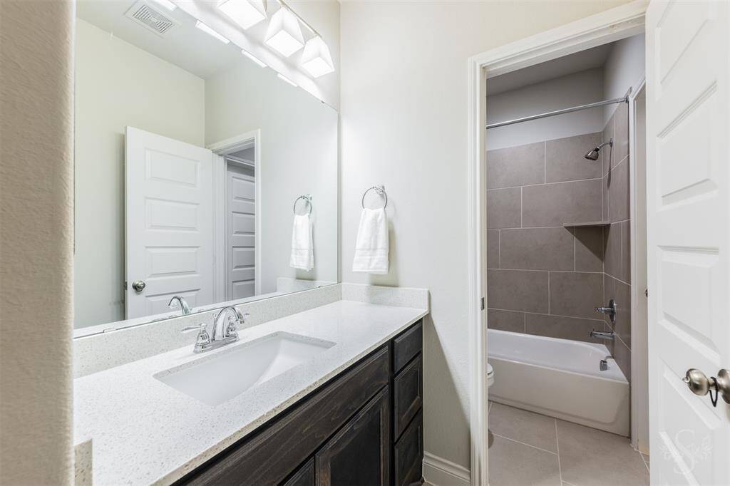 Connected to the Hollywood bath layout, the tub/shower combo features large-scale neutral tile for a clean, contemporary look. A practical setup ideal for busy households or guests.