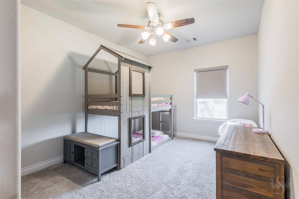 This charming secondary bedroom offers plush carpet, high ceiling, and a window with custom shade for added privacy. A versatile space that can serve as a guest room or children’s suite.