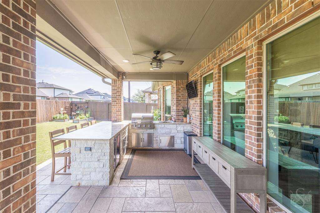This fully equipped outdoor kitchen includes stainless steel appliances, granite countertops, and a beverage fridge- ideal for effortless al fresco cooking. Overhead lighting and a ceiling fan ensure comfort from day to evening.