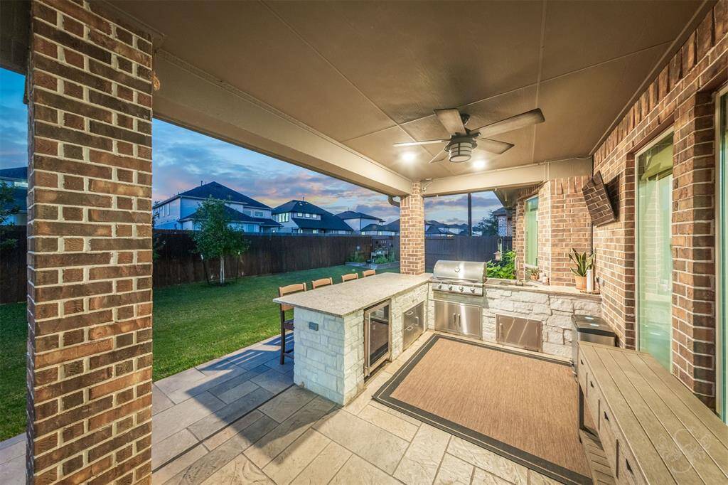 Enjoy outdoor dining beneath a charming pergola accented by stylish tile flooring and brick columns. The layout flows seamlessly into the main patio, offering multiple spaces for gathering and relaxing.