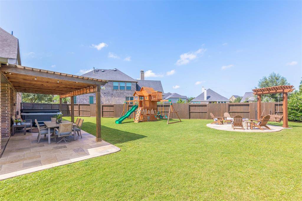 Imagine spending your days at this incredible outdoor living area features an extended covered patio with elegant columns, built-in outdoor kitchen, bar seating, and plenty of room for dining and lounging furniture. Surrounded by a pool-sized lush back yard, this space is perfect for elevated entertaining.