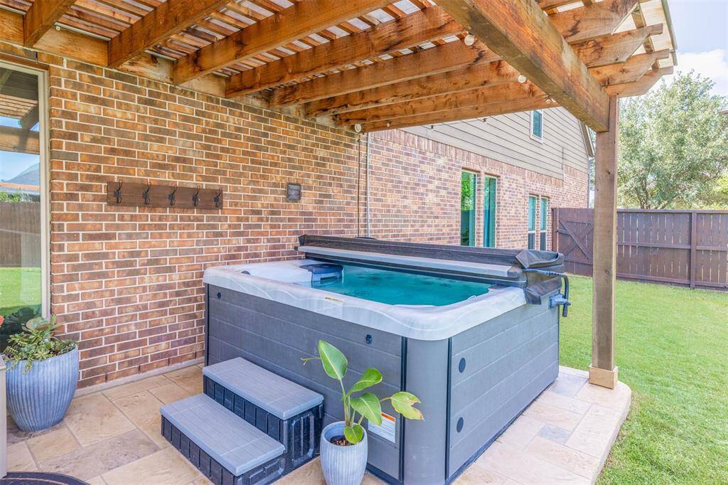Magnificent outdoor living area features an extended covered patio with elegant columns, built-in outdoor kitchen, bar seating, and plenty of room for dining and lounging furniture. Surrounded by a pool-sized lush back yard, this space is perfect for elevated entertaining and lots of play area for the kids.