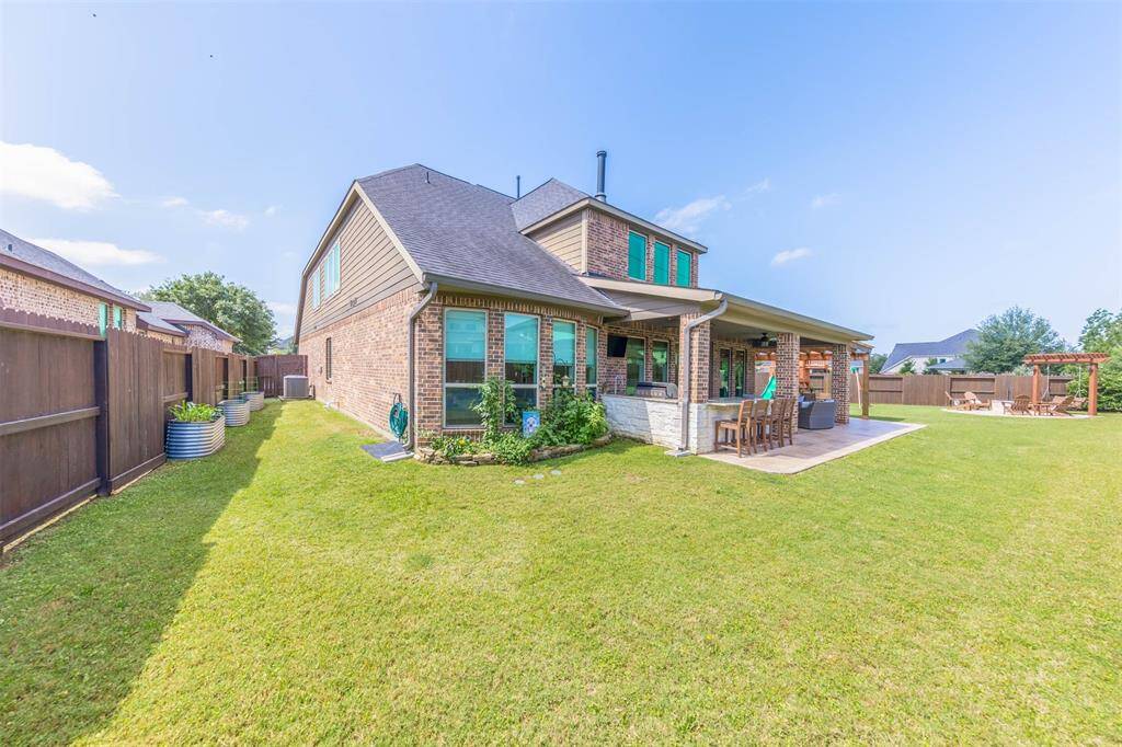 Enjoy outdoor dining beneath a charming pergola accented by stylish tile flooring and brick columns. The layout flows seamlessly into the main patio, offering multiple spaces for gathering and relaxing.