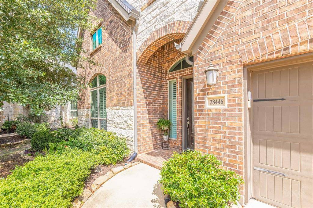 Charming brick and stone accents frame the inviting front entry, creating timeless curb appeal. Manicured landscaping and an arched doorway set the tone for the elegance that awaits inside.