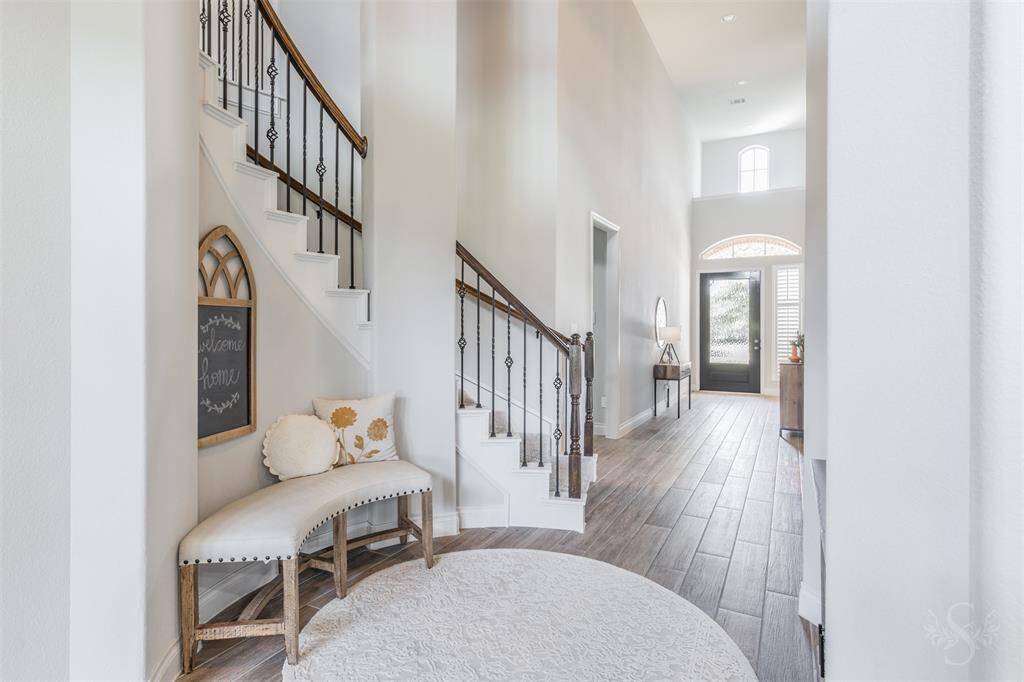 The welcoming foyer includes a charming sitting nook beneath the staircase, perfect for a cozy touch of hospitality. The graceful flow leads you into the heart of the home with style and ease.
