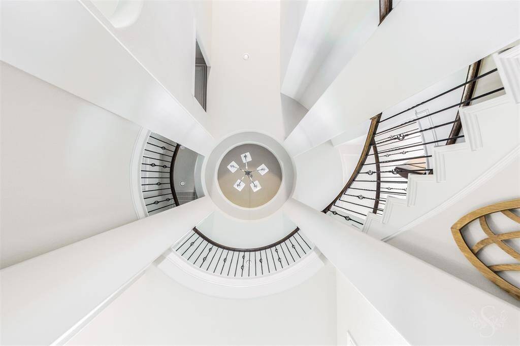 A breathtaking view of the soaring rotunda ceiling showcases architectural elegance with its dramatic curves and wrought iron detailing. This striking design feature sets the tone for the home's luxurious style.