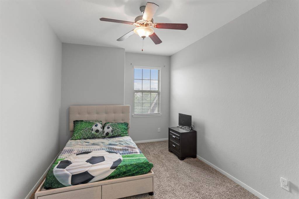 Wonderfully appointed secondary bedroom, featuring neutral paint, plush carpet, a window with privacy blinds, and a ceiling fan.