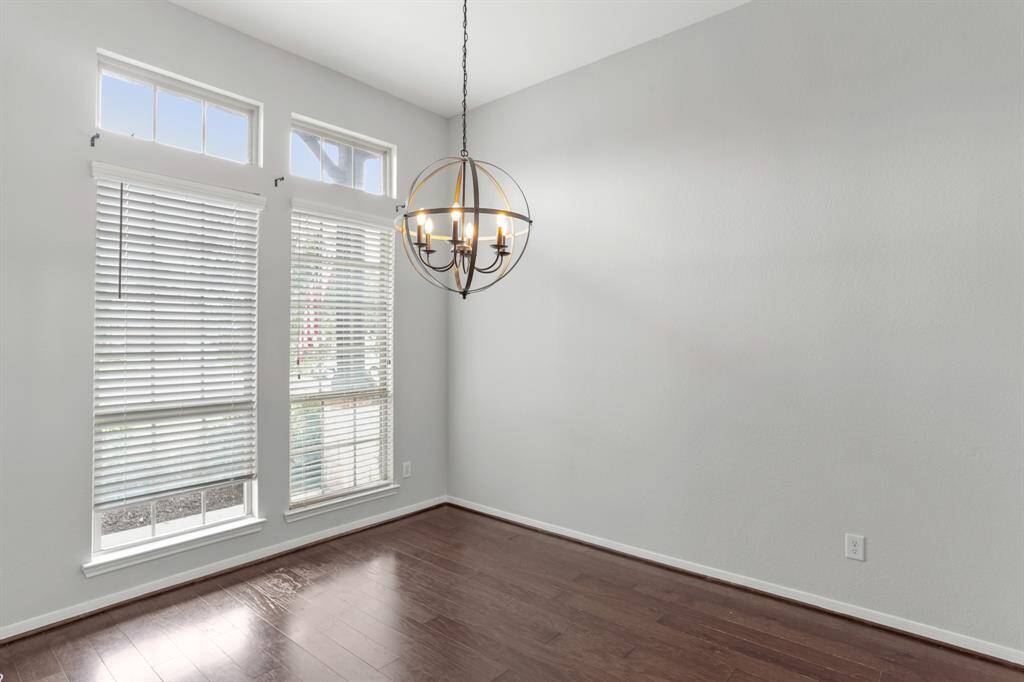Spacious dining room in the front of the house with wood floors, pendant lighting, and large windows with privacy blinds.