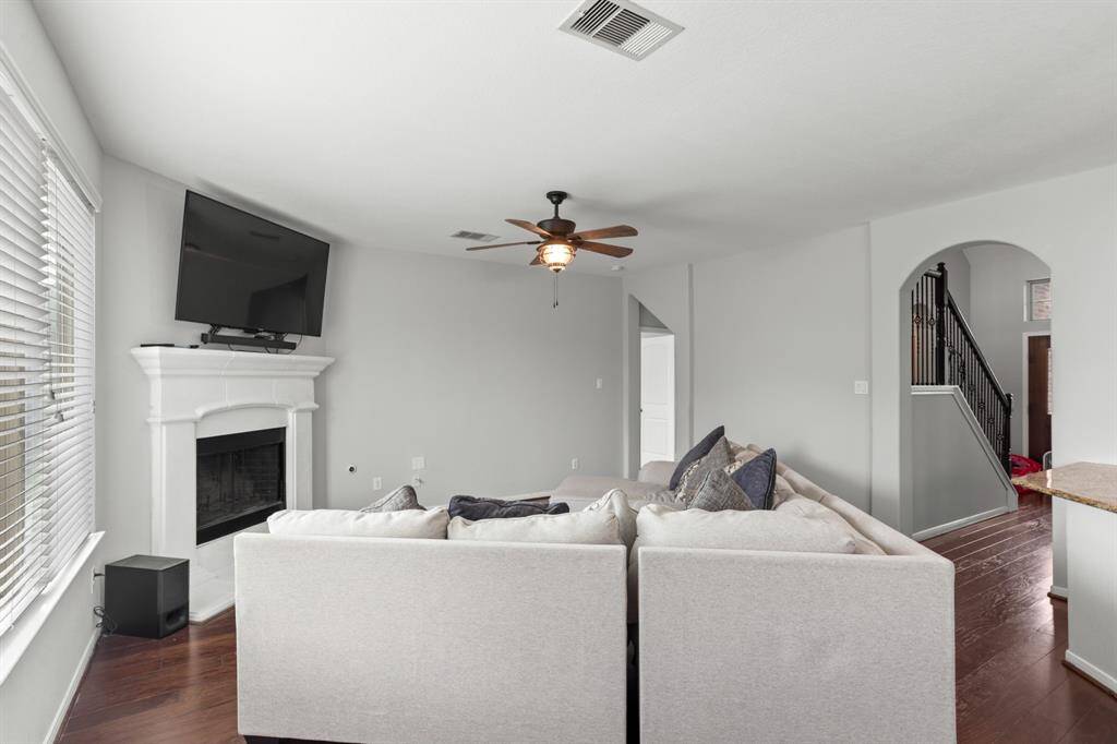 Walk through the foyer past the staircase and arrive at this incredible living room! Beautiful views of the backyard are provided by the incredible windows with privacy blinds. It is highlighted by a gorgeous fireplace, wood floors, and a ceiling fan.
