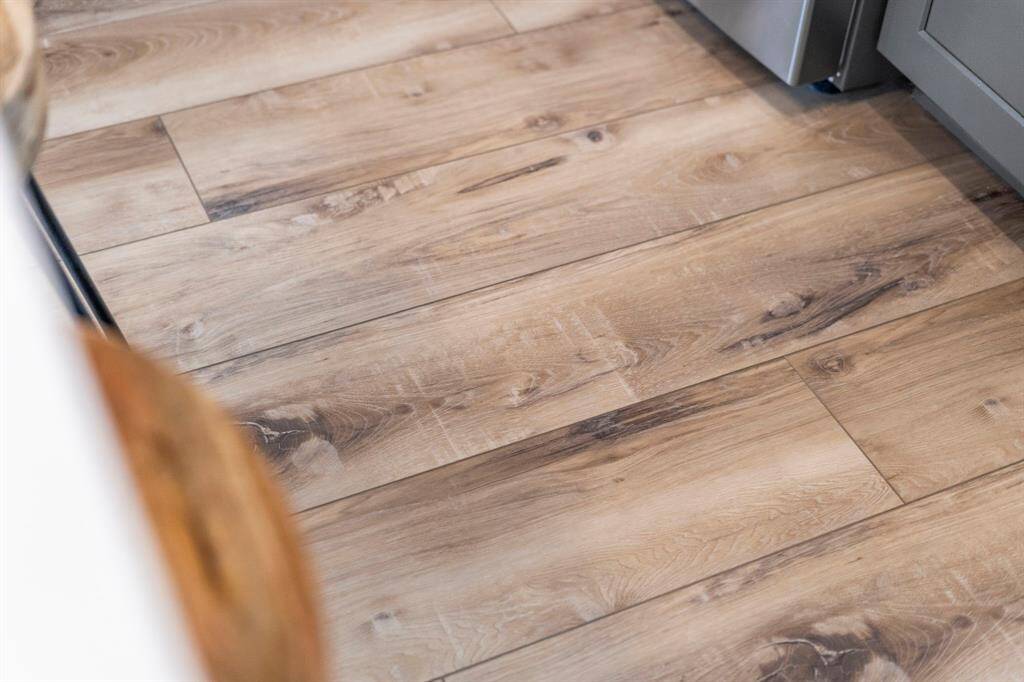 Rich, warm tones shine through in this close-up of the new (2022) large plank LVT Deerfield Hickory flooring, showcasing its beauty, durability, and timeless appeal.
