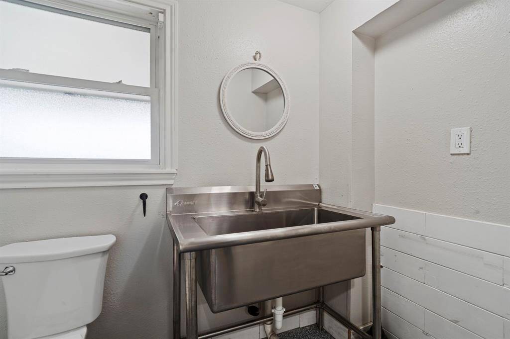 The guest half bath in the Game Room showcases a utilitarian, industrial-style stainless steel sink—combining function with edgy, modern appeal.