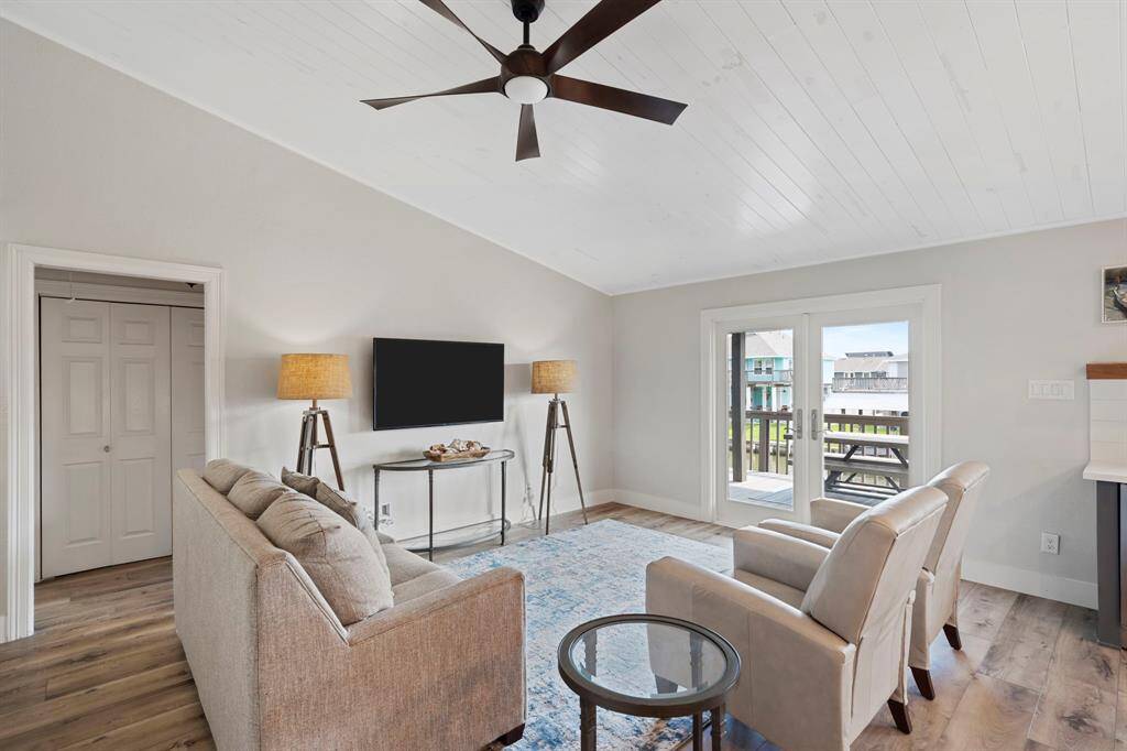 Inside, the spacious living room features gorgeous large plank LVT Deerfield Hickory flooring, a vaulted ceiling, and relaxing views of the water.