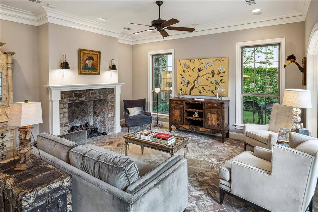 A marble-inset fireplace anchors the room with classic charm, while surrounding built-ins showcase treasures both collected and personal.