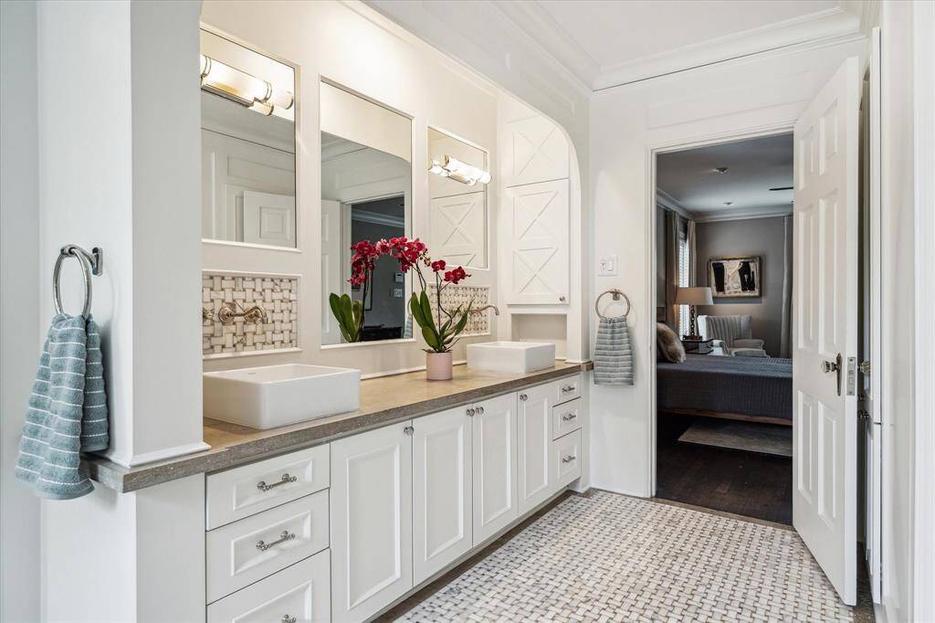 Designed for seamless mornings, the primary bathroom connects fluidly to the bedroom. Built-in cabinetry, dual mirrors, and sculptural lighting complete the refined aesthetic.