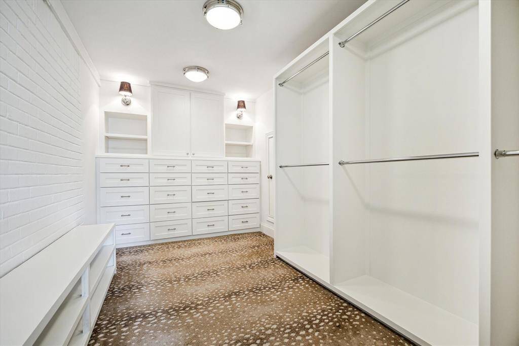 This expansive walk-in closet offers abundant storage with custom built-ins, open shelving, and hanging space.
