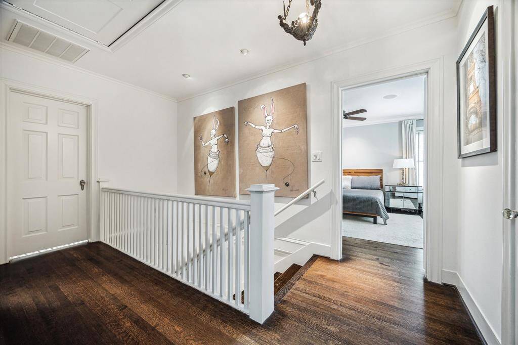 The upper landing doubles as a quiet gallery, featuring playful artwork and warm hardwoods. Natural light and charming details tie the upstairs rooms together beautifully.