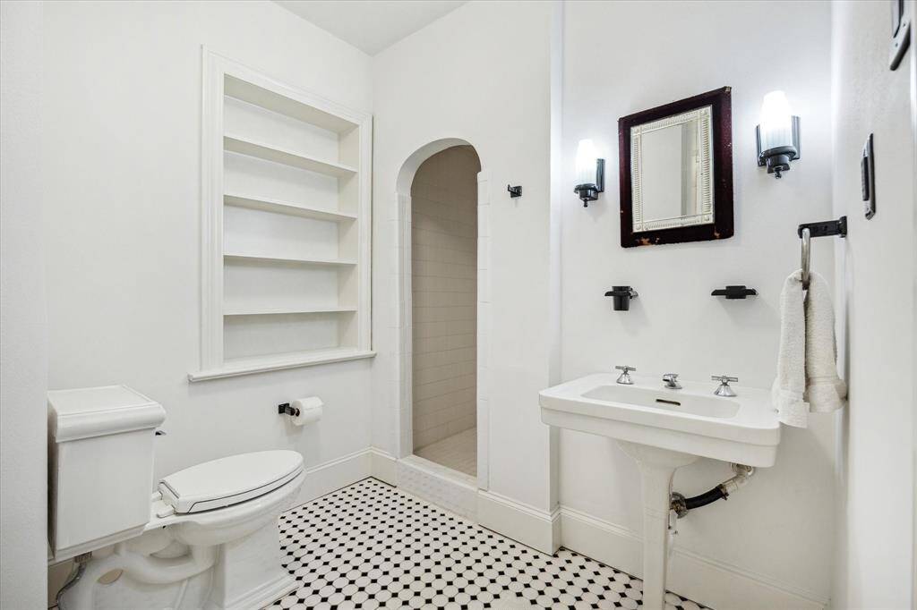 Vintage-inspired bathroom with black-and-white tile, built-in shelving, and a walk-in shower.